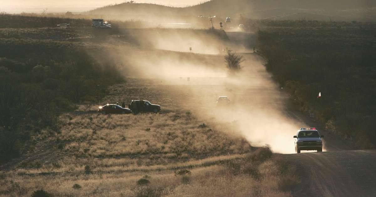 Customs and Border Protection vehicles driving near border of Southern United States in evening.